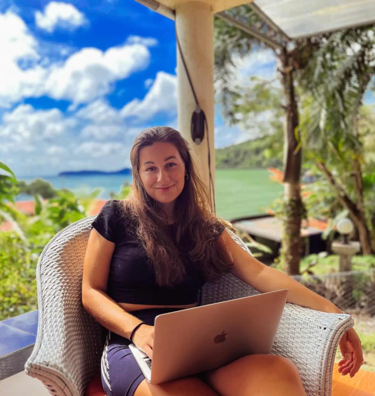 Kristína pracuje s notebookom na terase s výhľadom na more
